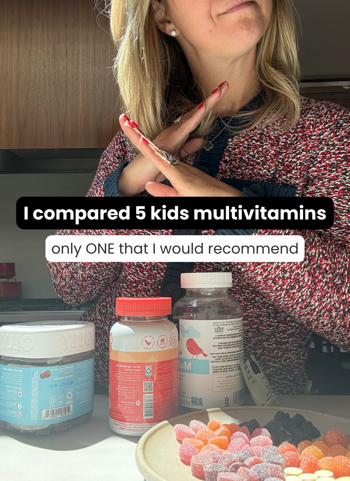 A woman stands behind a counter with four bottles of kids multivitamins and a plate of gummies. Text on the image reads: I compared 5 kids multivitamins&mdash;only ONE that I would recommend.